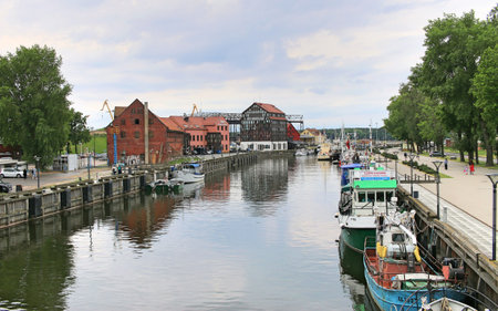 Entrance to the port of Klaipeda. Water channel, ships moored on the sides. The port buildings in...