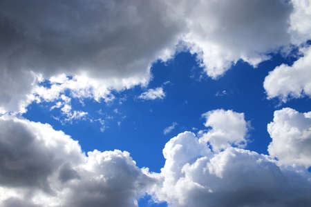 Clouds in the sky. White and gray fluffy clouds in the blue sky. A hole in the skyの写真素材