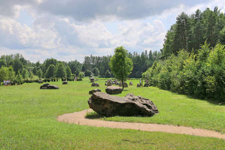 Huge erratic boulders in the megalith park. Big stones lie in the green grass. There are green trees around. Silvarium, a forest park in the Poczopek, the Krynki Forest District. Podlasieの写真素材