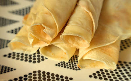 Yellow rolled shortbread Polish pancakes served on a black and white plateの写真素材