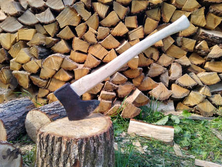 An ax stuck in a stump. Chopped wood in the backgroundの写真素材