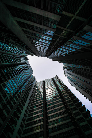 Low angle shot of modern glass city buildings with clear sky background.