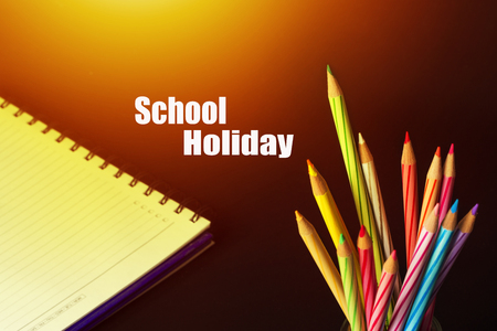 Concept of School holiday  with inscription, color pencils on black background with flare.の写真素材