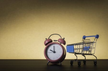 Small shopping cart and alarm clock on pastel background minimal creative conceptの写真素材