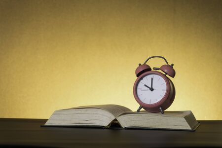 Symbolic hard study is powerful to succeed, concept with book and alarm clock. Time in business and...
