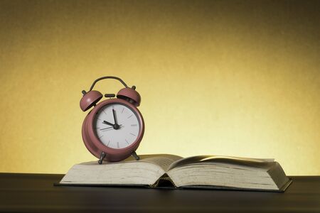 Symbolic hard study is powerful to succeed, concept with book and alarm clock. Time in business and...