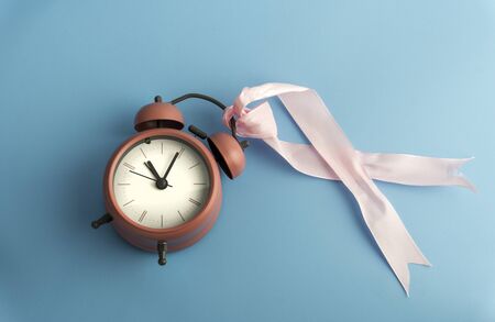 Breast cancer concept with ribbon, time and pink flower isolated by blue back ground.の写真素材