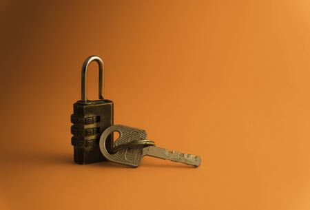 Combination padlock and key isolated on orange background. Business to success concept.の写真素材