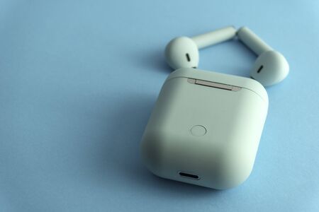 Bluewireless earphones or headphones, plastic case or box for storage and charging and smartphone on...