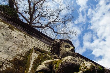 Old walls and statue with a background of dead trees and clear skyの写真素材