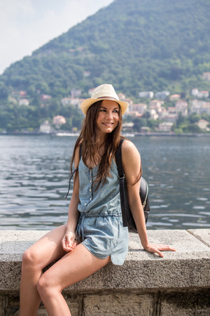 Smiling attractive girl sitting by the lake enjoying the view summer dayの写真素材