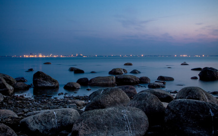 Beautiful sunset on the sea, city lights on the horizonの写真素材