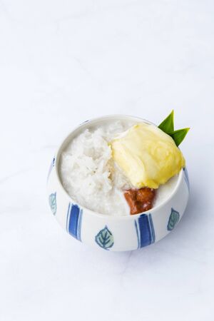 Sweet Sticky Rice With Durian And Coconut Milk Sauce,Thai sweet sticky rice with durian, Thai style tropical dessert,  isolated on white background, selective focus.の写真素材