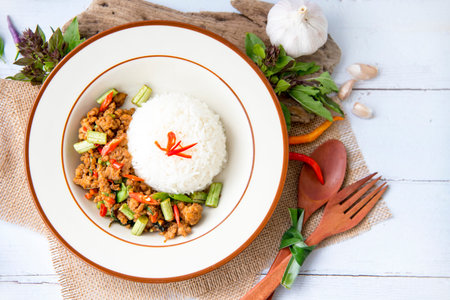 Fried Stir Thai Basil chicken in bowl with  ingredient materials are basil leaves, chili and garlic, This thai inspired meal is perfect for a quick lunch or served as side dish,Thai delicious spicy food.の写真素材