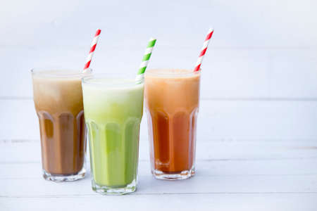 Ice milk coffee, green tea, Iced Thai milk tea drink in tall glasses  isolated on white wooden table background, Selective focus, Cold drinks so delicious and snack, copy space.の写真素材