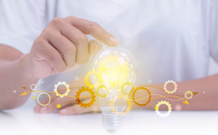 Hand holding gears in a light bulb, conceptual mechanism of ideas, showing the creativity,...