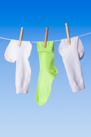 White and green socks with dolly pegs hanging out on washing line against blue backgroundの写真素材