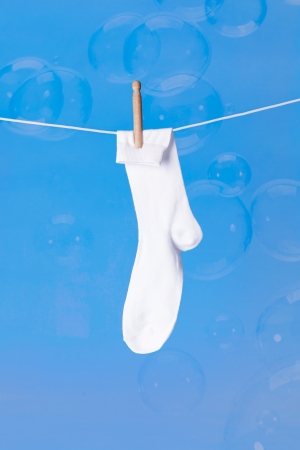 white sock on washing line with bubbles on blue backgroundの写真素材