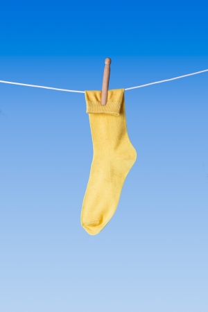 yellow sock on washing line against blue backgroundの写真素材