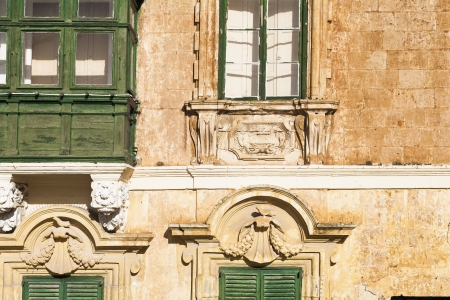 Old wooden doors windows and elaborate stone work on house on the island of Maltaの写真素材