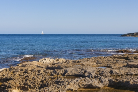 SIngle yacht on blue sea with rocky beach on the island of Maltaの写真素材