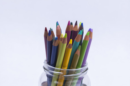 Artists coloured pencils in glass jar on white background for hobbies and leisure timeの写真素材