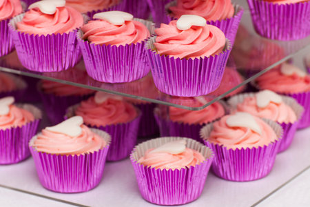 Pink cupcakes with white sugar hearts on cake standの写真素材