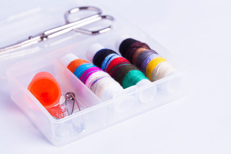 Miniature sewing kit with scissors isolated on white for concepts of domestic chores and...