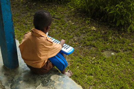 A boy playing a keyboard in a public park.の写真素材