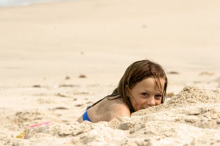 Young girl playing on the beach in the sand shot with shallow DOFの写真素材