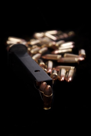 Close up of loaded gun magazine and ammunition isolated on blackの写真素材