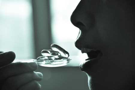 Women eating Cod liver oil omega 3 gel capsules in the spoon. Medicine, Medical health care, Healthy Foodの写真素材