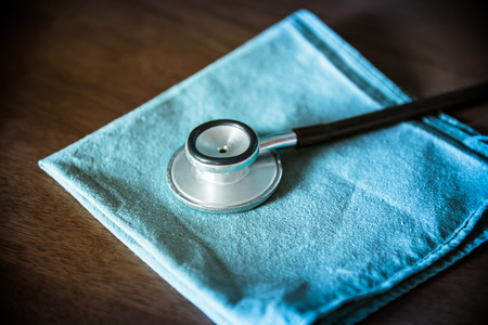Stethoscope with green surgery uniform for doctor coat on wood table  backgroundの写真素材