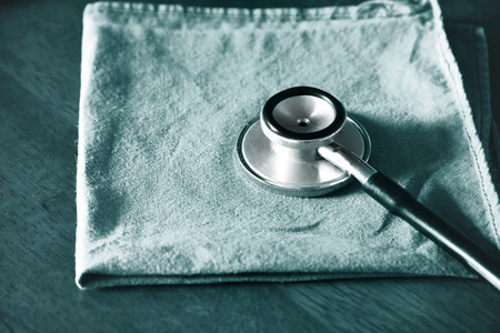 Stethoscope with green surgery uniform for doctor coat on wood table  background In the operating room, Medical health care in hospitalの写真素材