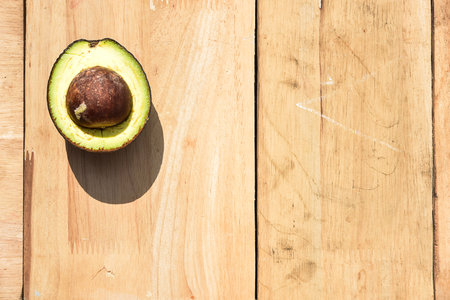 Half avocado on wooden board