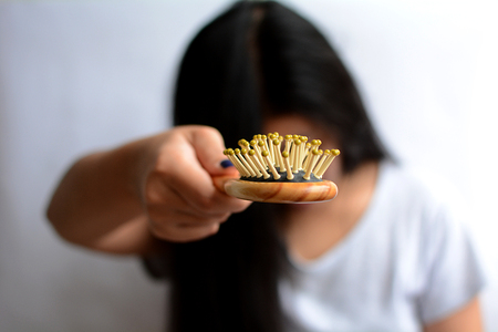 Hair loss, hair fall everyday serious problem, girl with a comb and problem hair on white background.の写真素材