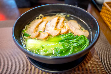 Japanese style noodle soup with pork in black bowl.の写真素材