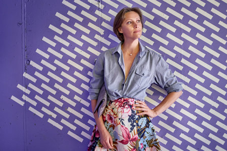Beautiful young woman in a fashionable shirt and a long colored skirt on a blue background.