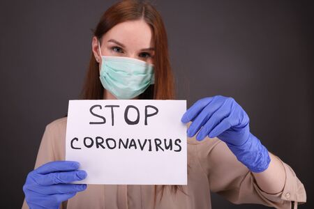 Woman tears sheet of paper with sign "stop coronavirus"の写真素材