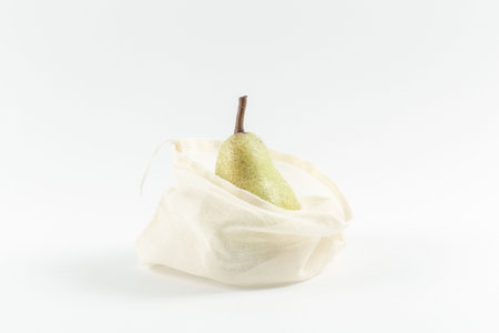 Beautiful juicy green pear in an eco bag on a white background. Proper nutrition.