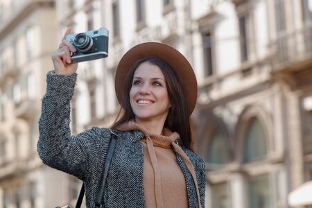 Beautiful brunette tourist girl holds a camera in her hands and looks into the lens.の写真素材