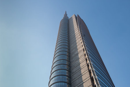 The top of a huge multi-story modern office building against a blue sky. 01.2020 Milan.
