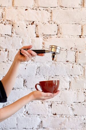 Cup with fresh coffee on a background of a white brick wall. Making delicious aromatic coffee.の写真素材