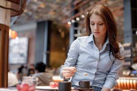 Young beautiful girl in a blue shirt in a beautiful fashionable cafeの写真素材