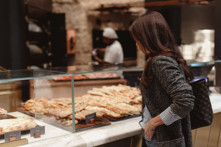 Beautiful girl near a shop window with bakery productsの写真素材
