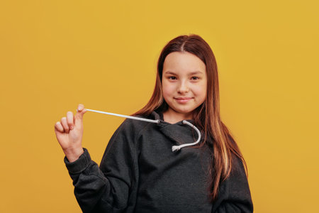 Young happy girl on a bright background pulls the drawstring from the sweater to the side.