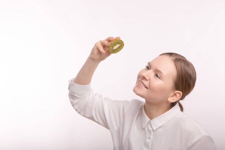 Girl holding a kiwi on whiteの写真素材