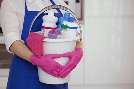Cropped photo of a girl with a bucket in her hands. Against the background of a white beautiful modern kitchenの写真素材