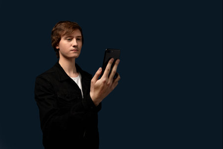 A guy with a serious haircut looks into a cell phone.