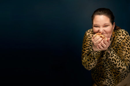 Overweight girl in a leopard blouse with a hamburger in her hand.